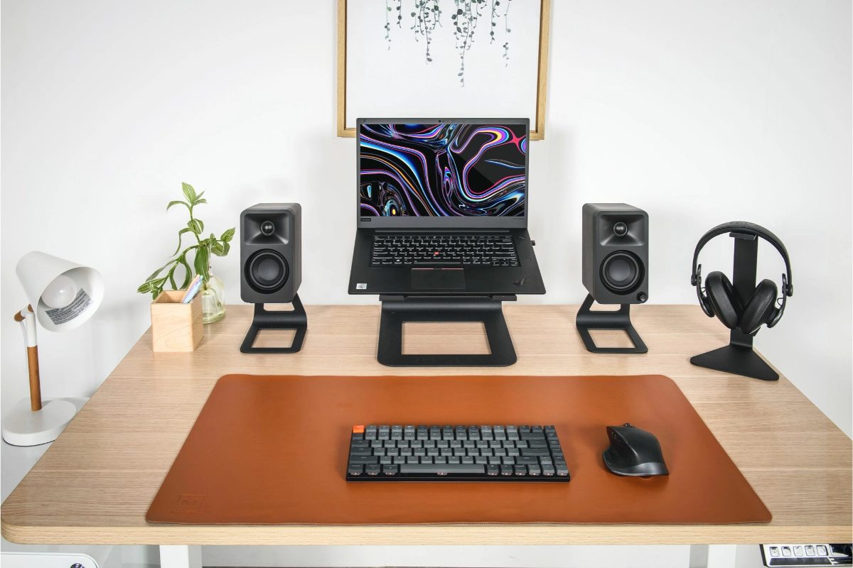 Kanto H1 Universal headphone stand on desk holding headphones next to speakers and laptop