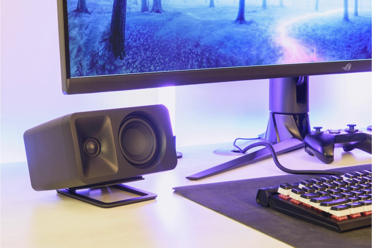 Kanto s2 Angled Desktop Small Speaker Stand in black with speaker laying sideways under gaming monitor on desktop