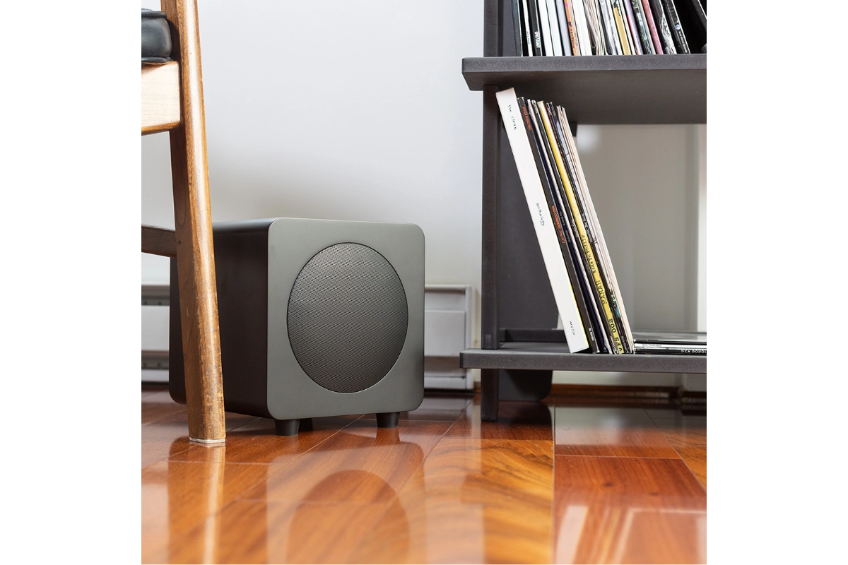 Kanto sub8 Powered subwoofer sitting beside record shelf, elevated from hardwood floor
