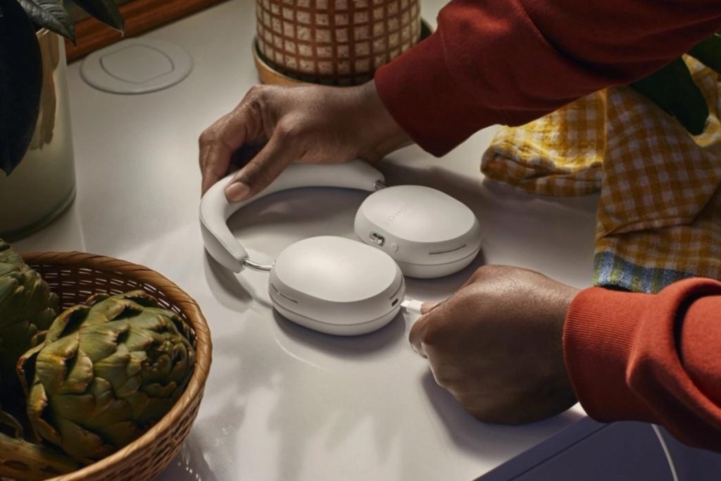 Someone plugging in a pair of white Sonos Ace headphones.