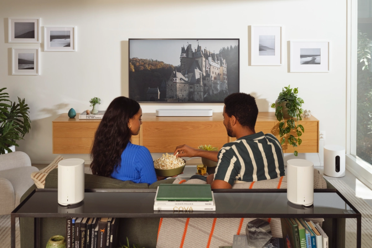 Sonos Immersive Set Beam set up in a living room, paired with two era 100 speakers. A couple are watching a movie