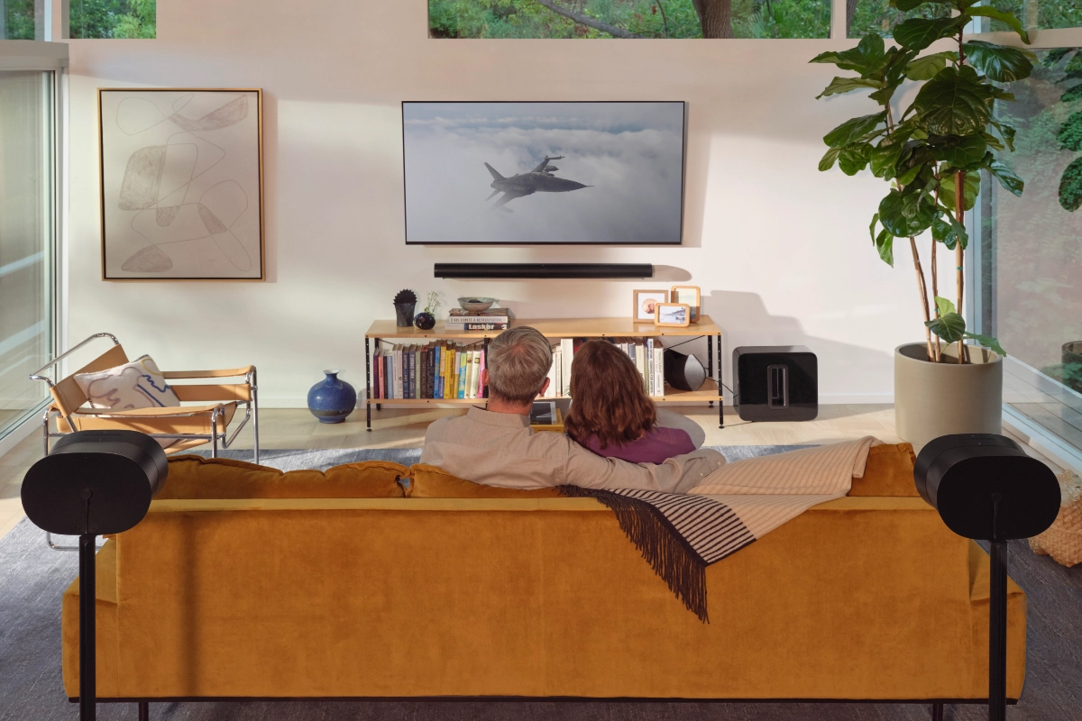 Sonos Ultimate Immersive Set with Arc in black, setup in a living room with a couple watching a movie on the couch