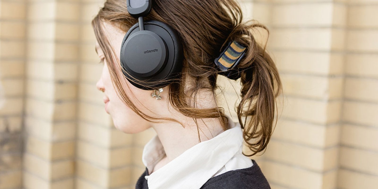 Young female wearing Urbanista Los Angeles solar power headphones in black
