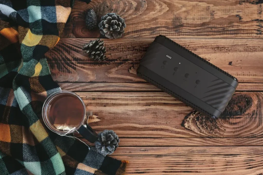 A cozy scene featuring a Klipsch Nashville portable speaker, a steaming cup of tea, and a soft blanket, perfect for relaxation.