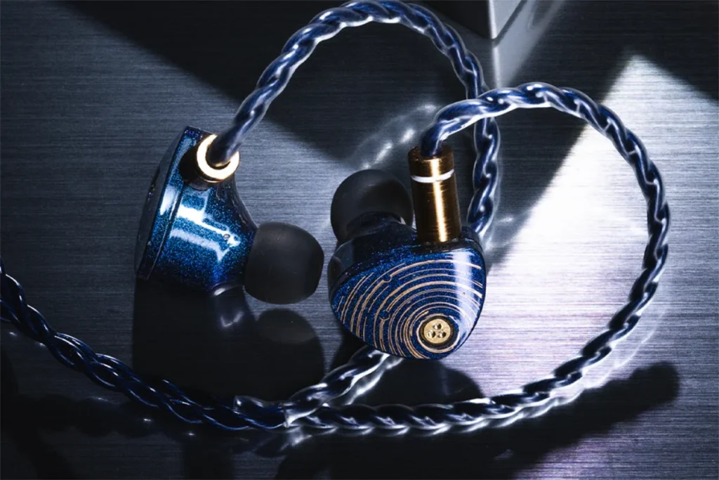 Moondrop Starfield II Earphones lifestyle image, earphones with cable attached, resting on black shiny table