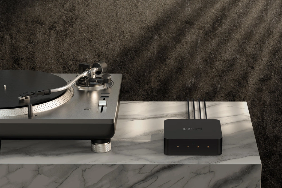 Wiim Pro Music Streamer sitting on marble table, beside and plugged into vinyl record player
