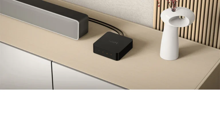 Wiim Pro Music Streamer sitting atop a cabinet, underneath TV, plugged into soundbar