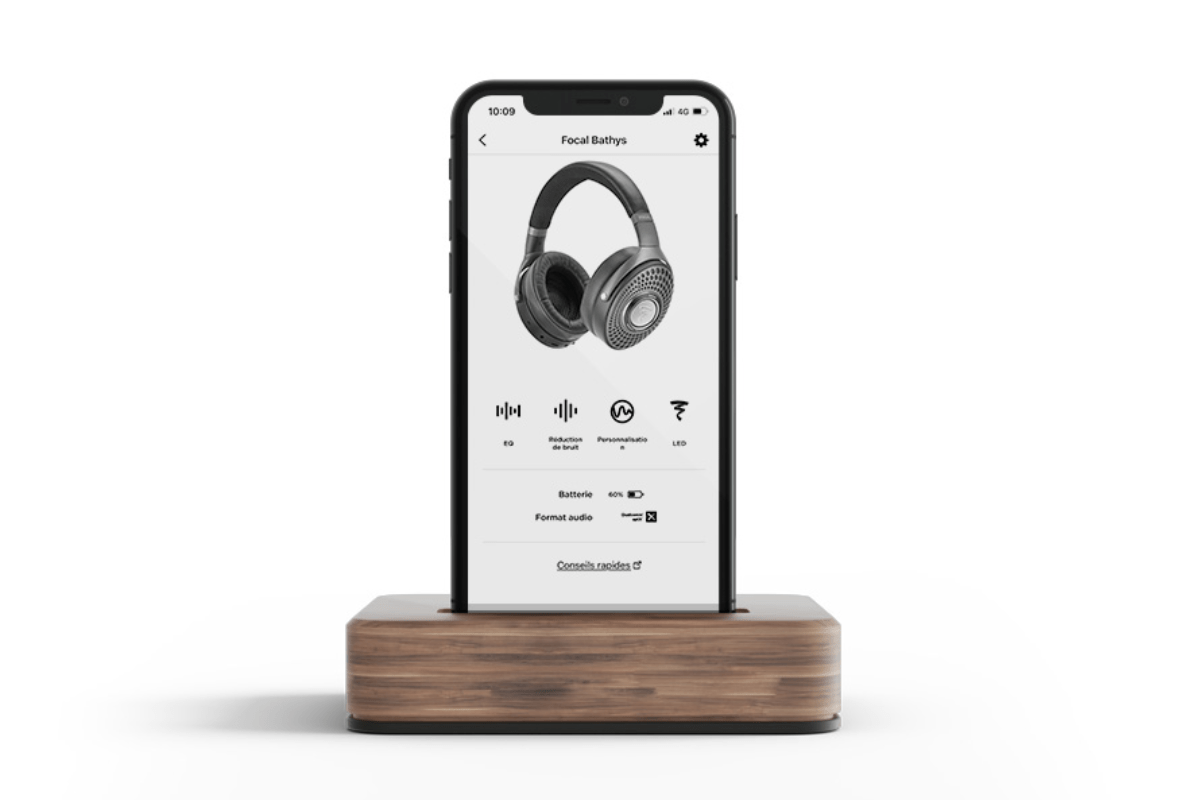 A wooden stand holds a phone adorned with Black Silver Focal Bathys Headphones, showcasing the Focal/Naim App interface.