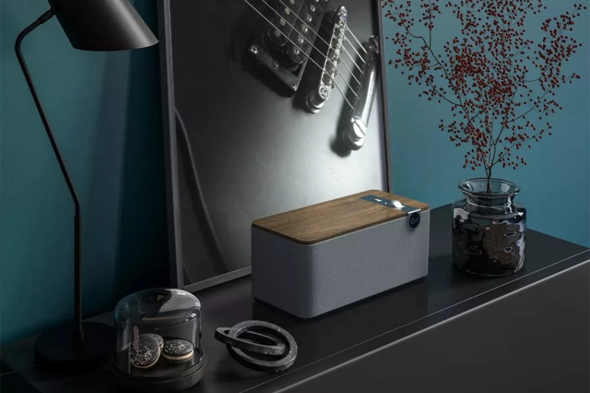 The Klipsch The One Plus speaker is placed on a wooden table, showcasing its compact design and elegant finish.
