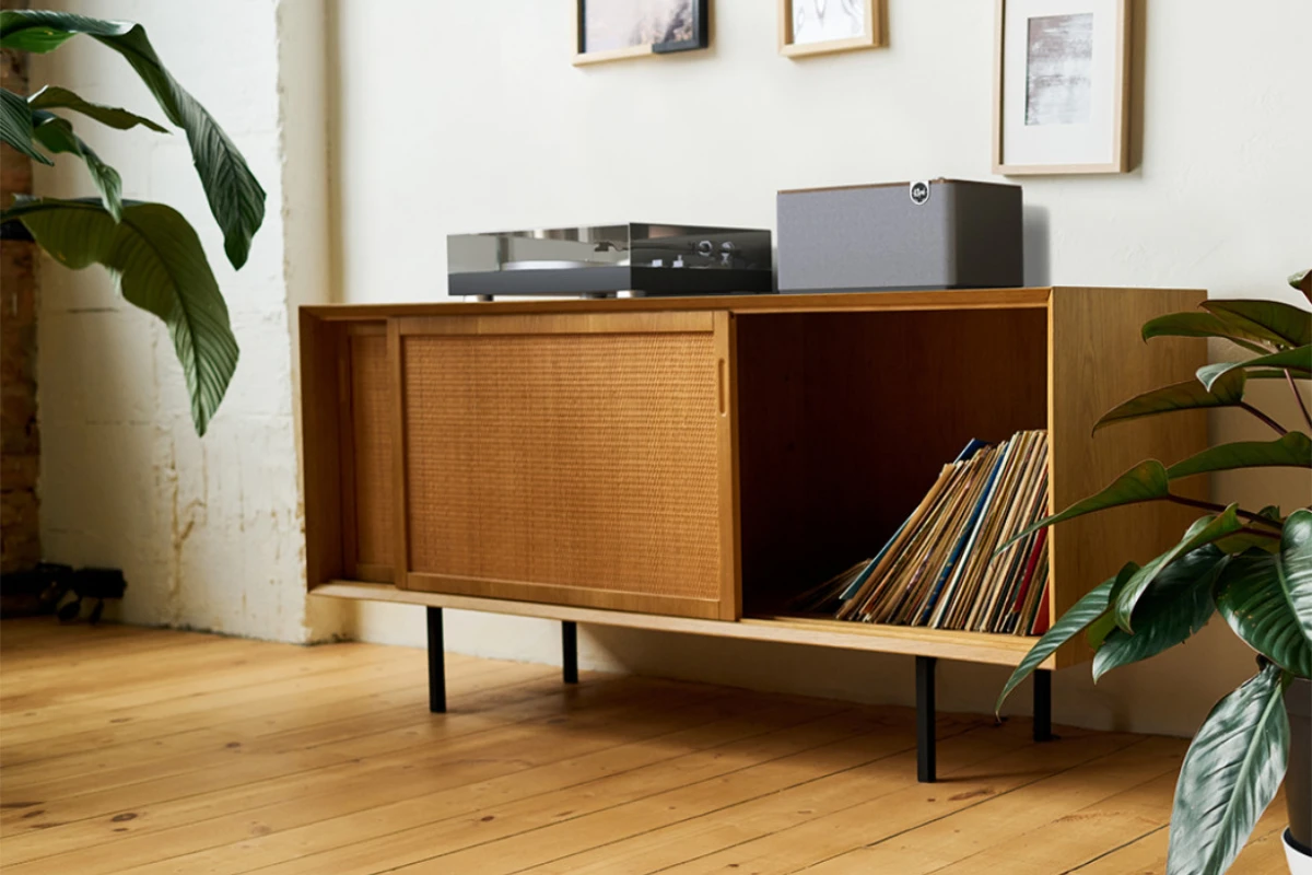 Klipsch Three Plus Walnut speaker resting on a credenza that houses vinyl records and a record player, highlighting its phono connectivity