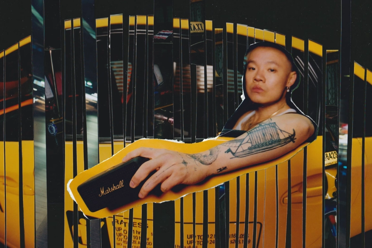 A man with arm tattoos is holding the Marshall Emberton III speaker