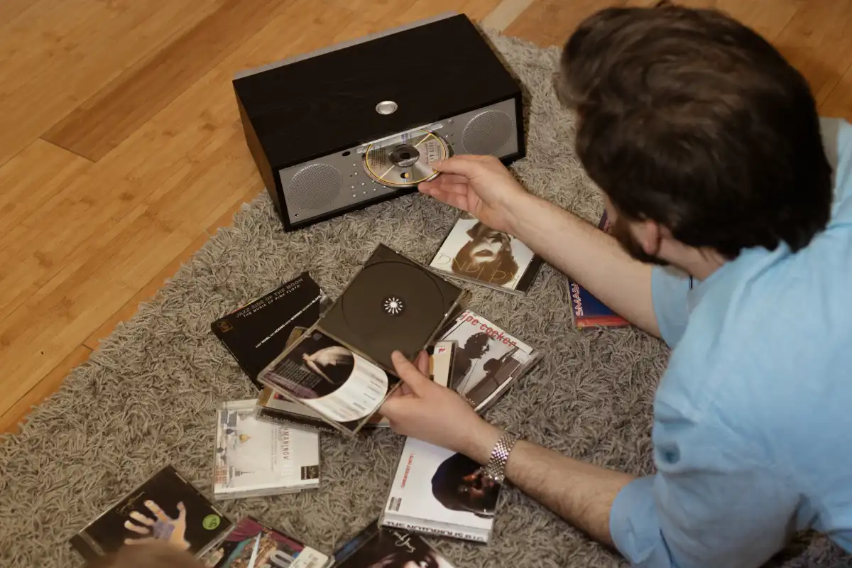 A man wearing a blue shirt is positioned near the Tivoli Music System BT, emphasizing the blend of style and technology.