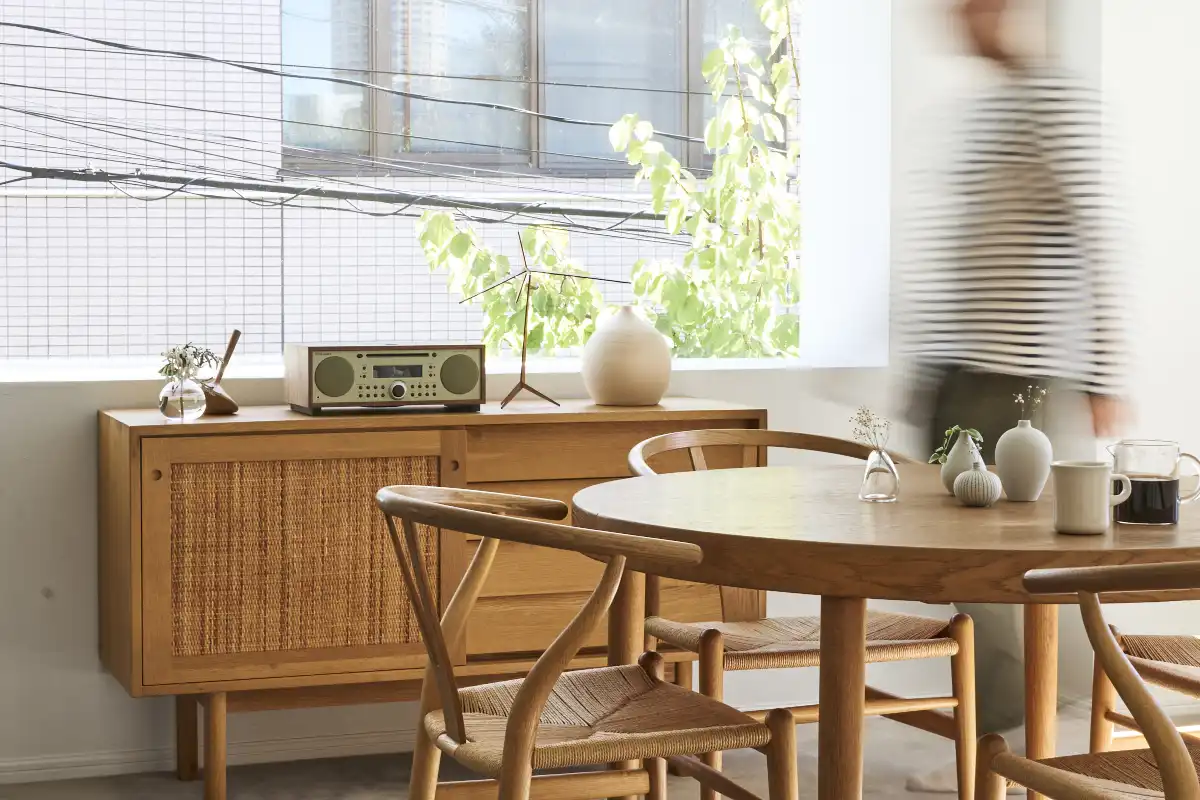 A wooden table surrounded by chairs, featuring the Tivoli Music System BT elegantly placed on top.