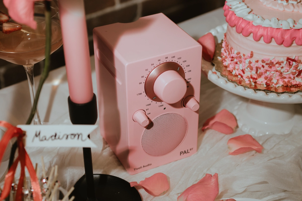The Tivoli Pal BT, a pink radio, is displayed on a table, emphasizing its chic appearance and functionality