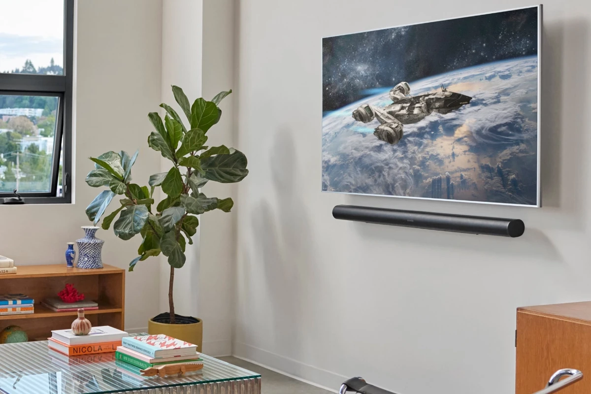 A family watches tv while sound is played through a wall mounted sonos arc ultra soundbar in black