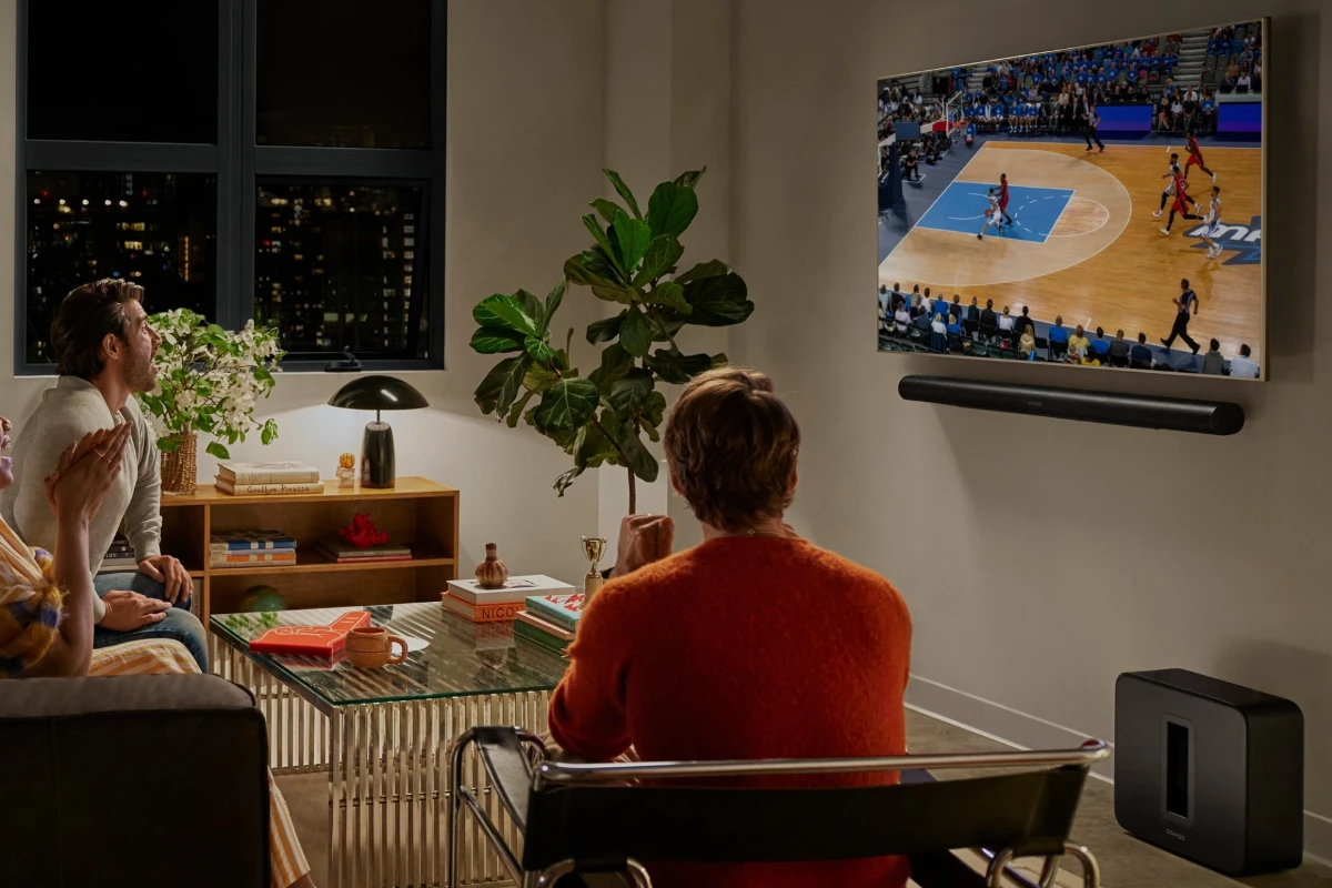 Friends watch sports on tv while sound is played through a wall mounted sonos arc ultra soundbar in black