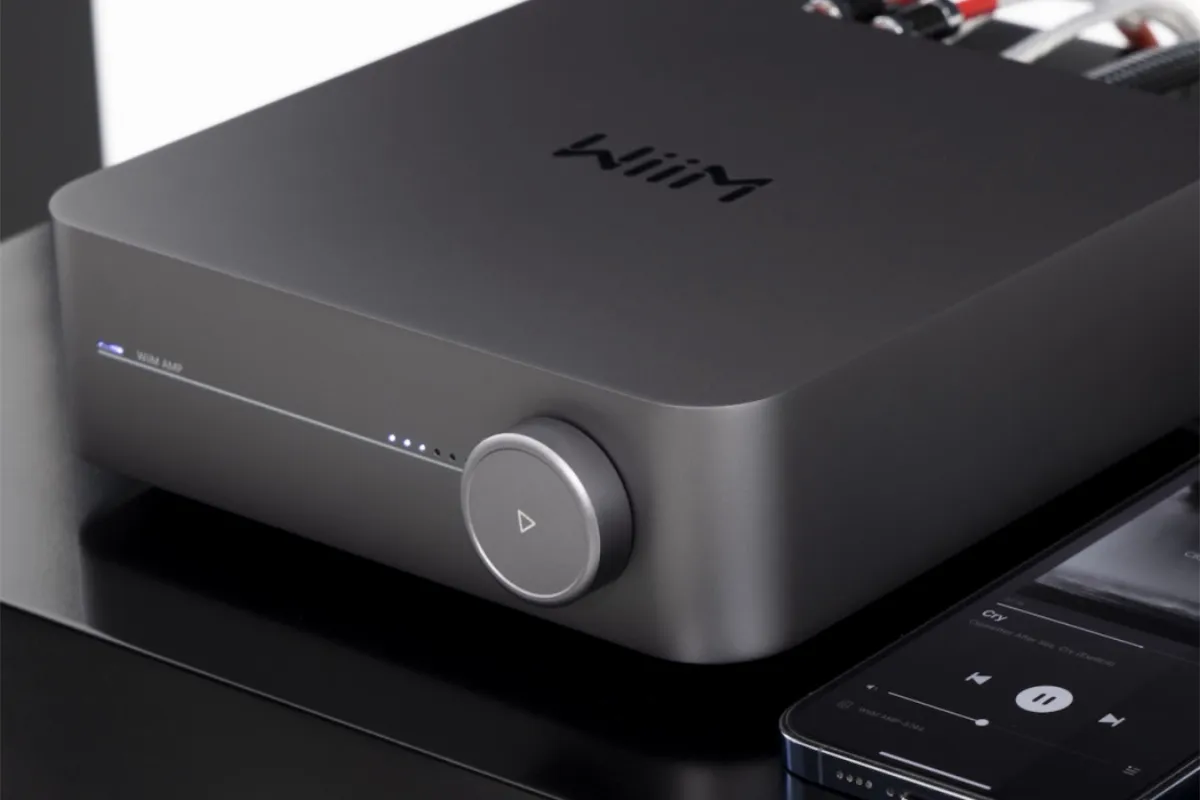 Wiim amp in grey rests beside a cell phone playing music through the wiim amp