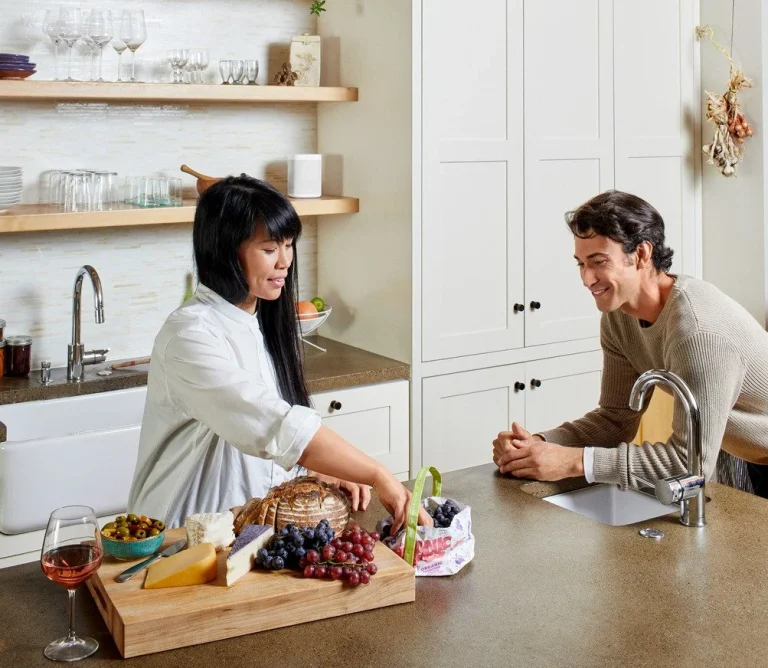 Two people in a kitchen fixing a snack with a Sonos Era in White in backgroune