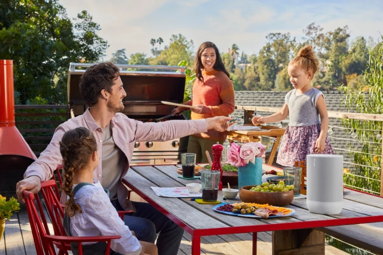 A family enjoying a meal outdoors with a sonos move 2 speaker on the table