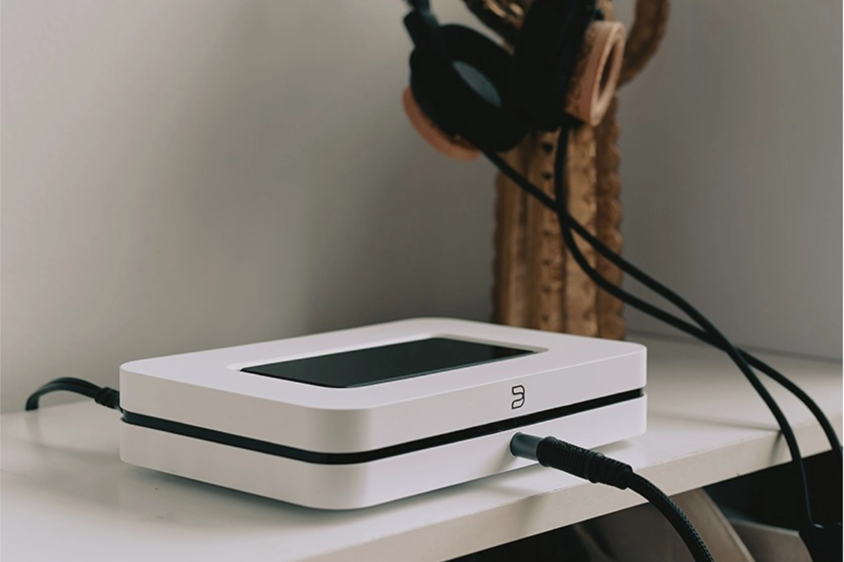 Blue sound node in white 2024 version on shelf beside speakers